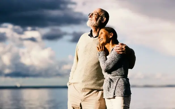 Casal aposentado sorrindo à beira-mar